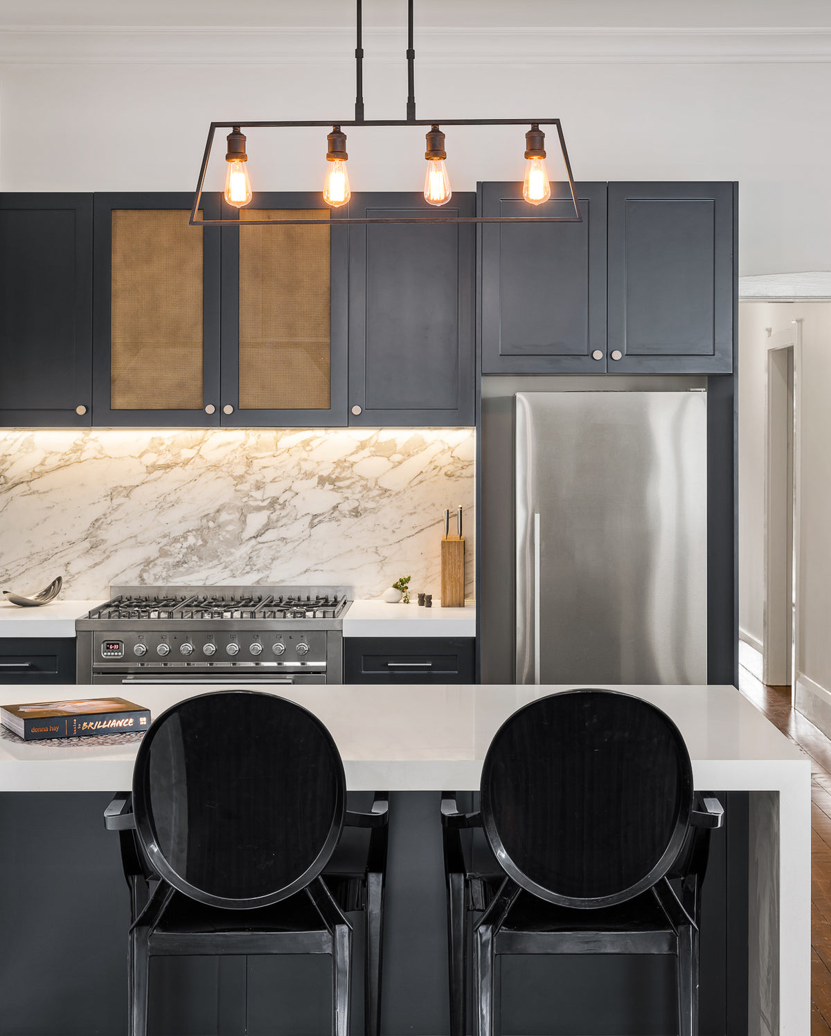 Dark kitchen cabinetry with pendant lights and a marble-patterned splashback