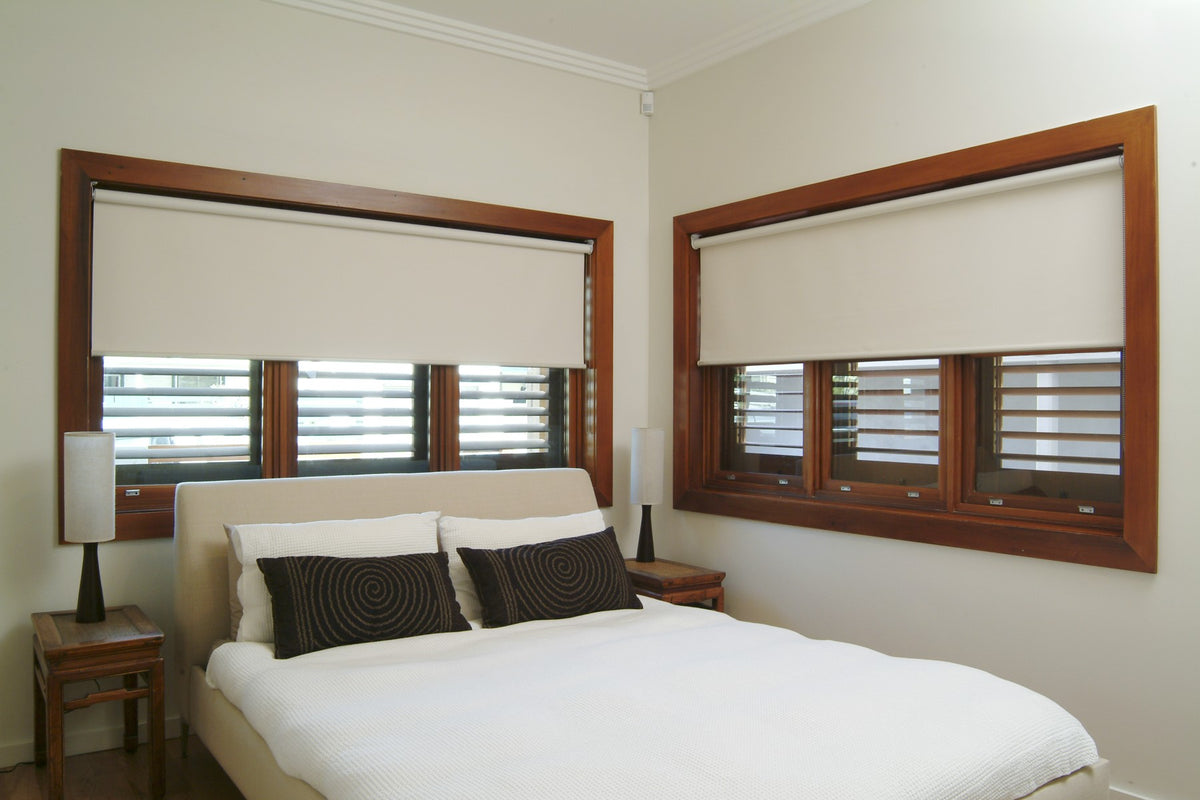 Helioscreen products: pale roller blinds above timber-framed bedroom windows.