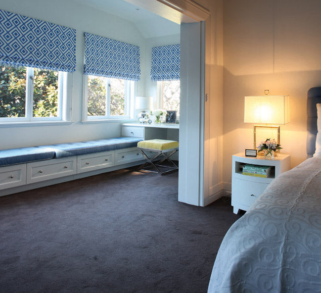 Bedroom with blue patterned Roman blinds and a window seat