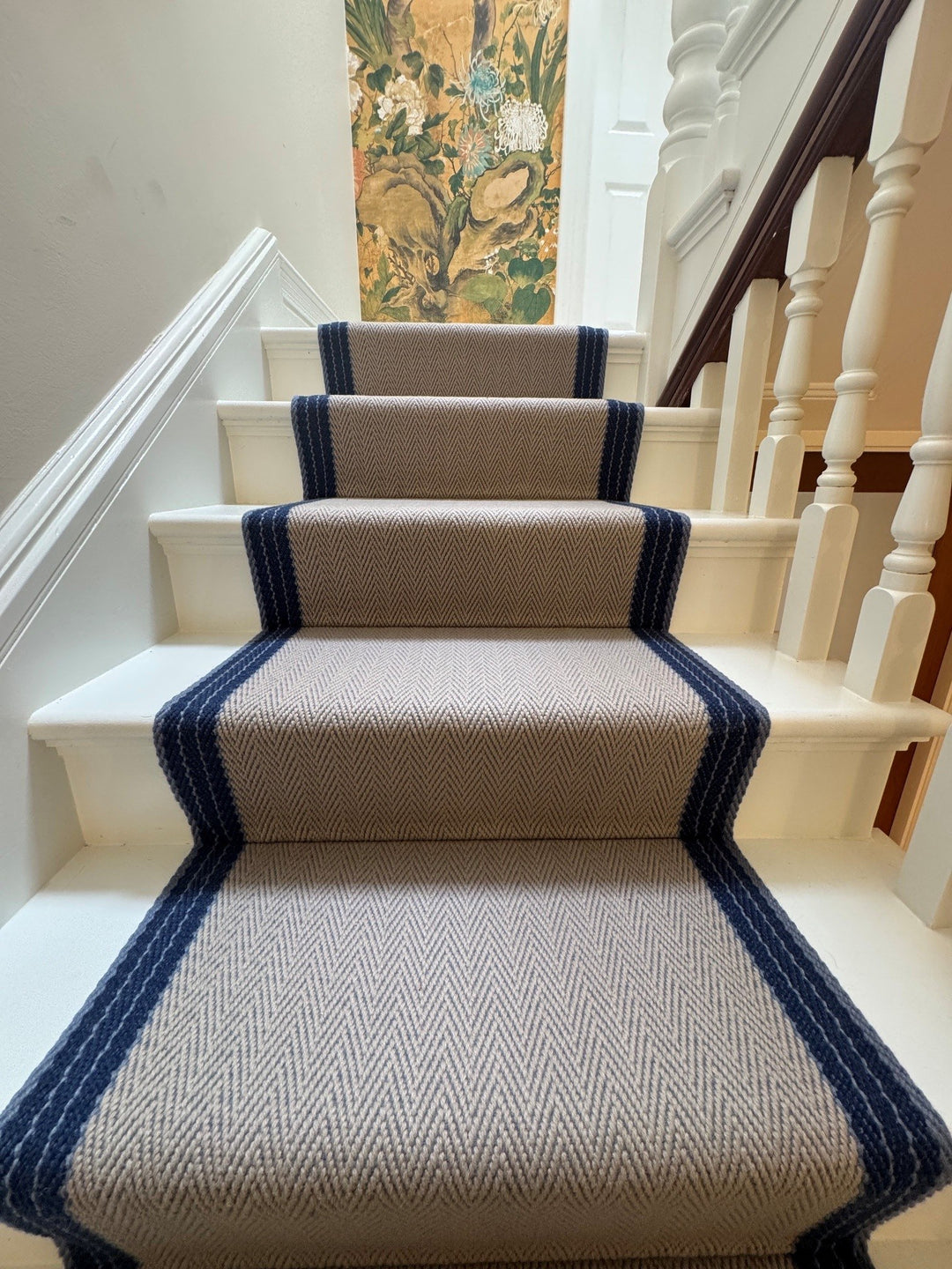 Botanical wallpaper beside a stair runner with navy borders
