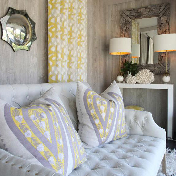 Pale button-tufted sofa with yellow and grey patterned cushions in a styled interior.