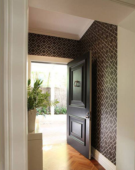 Entrance hallway with patterned wallpaper and a dark timber door