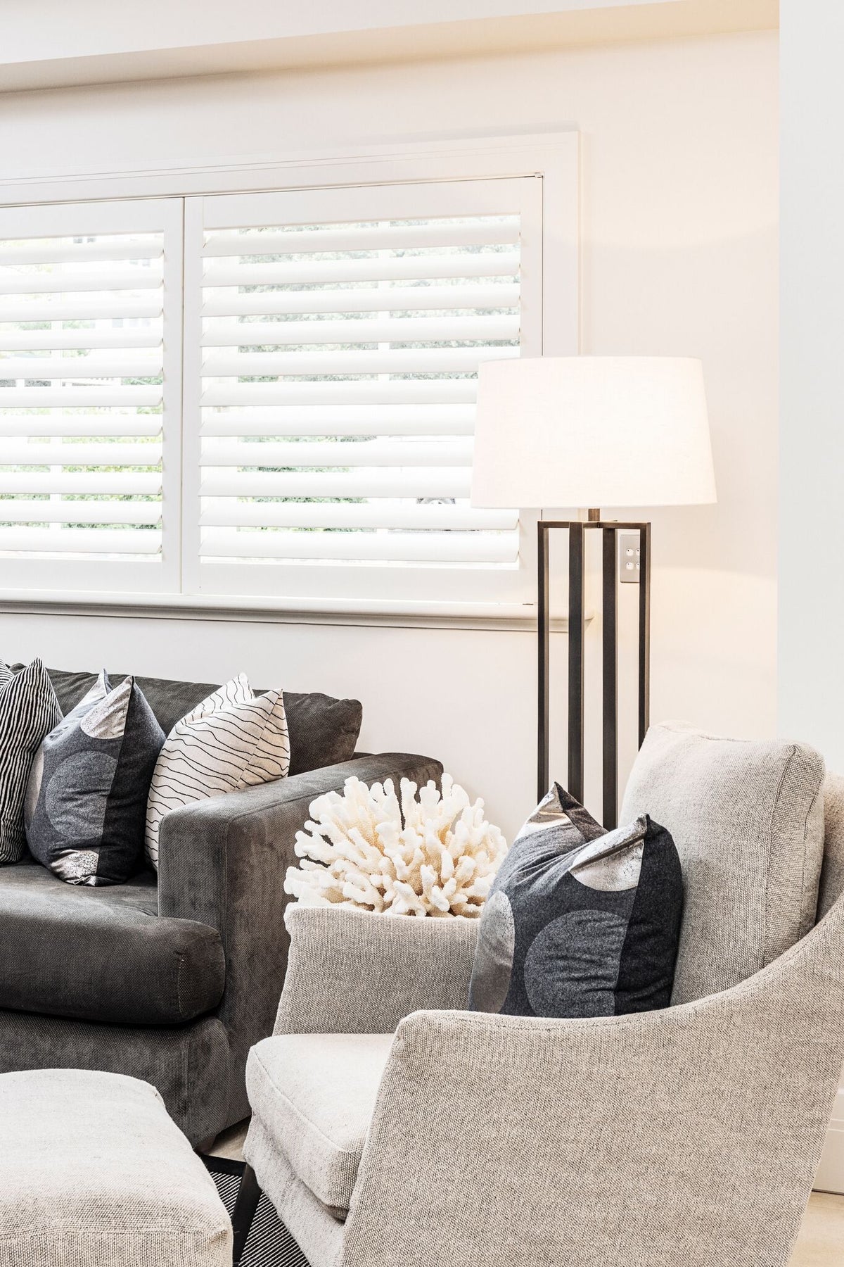 Two upholstered chairs with a table beside white shutters