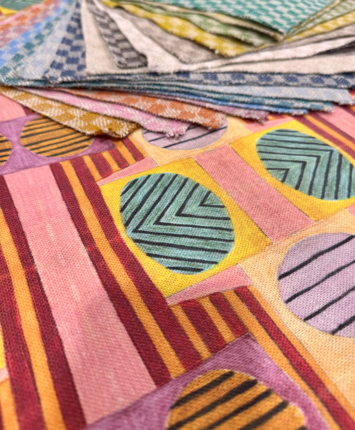 Colourful geometric patterned fabric samples arranged in overlapping layers