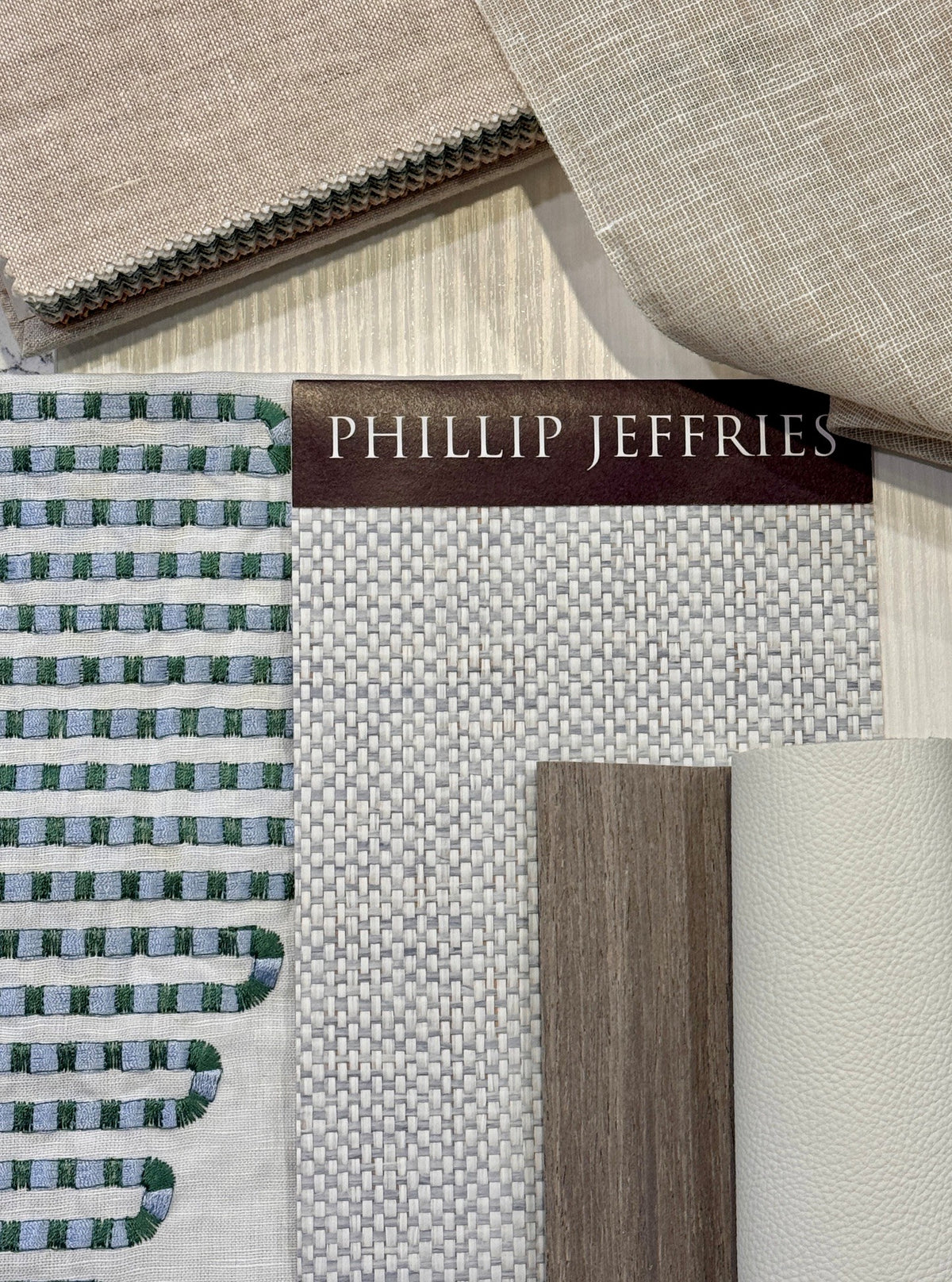 Cream and green textile and finish samples with a labelled wallcovering swatch