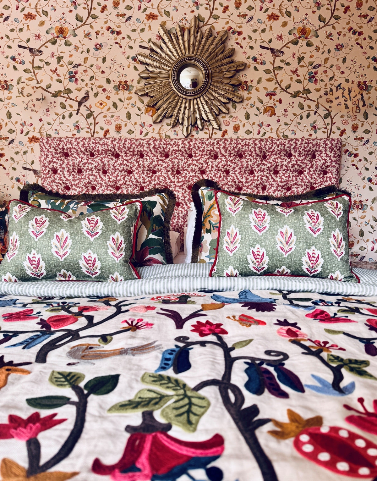 Patterned upholstered bedhead with coordinated cushions, floral bedding and botanical wallpaper