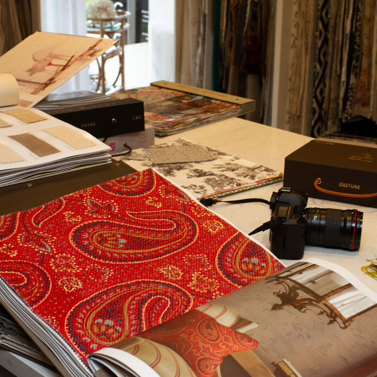 Red patterned fabric and coordinating samples on a worktable