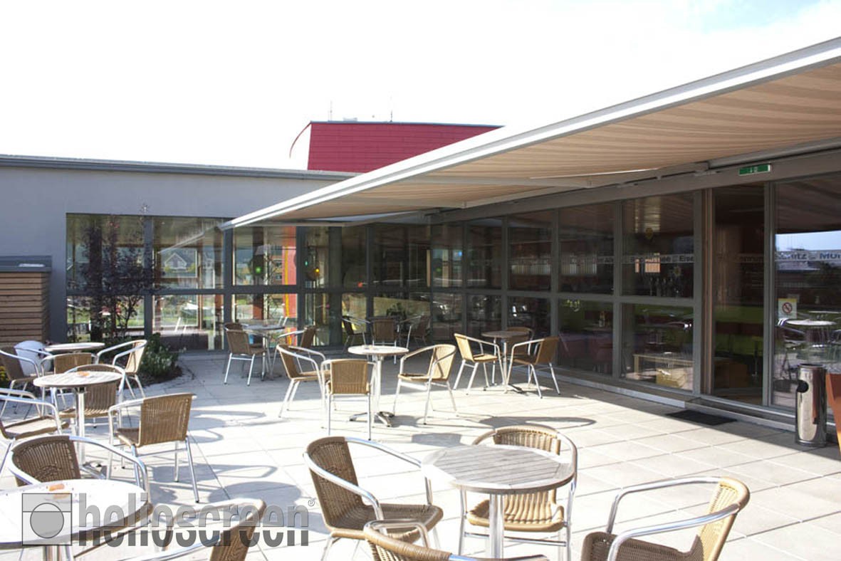 Helioscreen products: a retractable awning shading an outdoor cafe terrace.