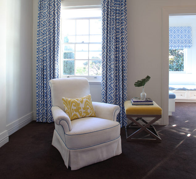 Pale armchair beside patterned curtains