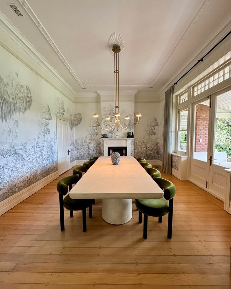 Dining room with a long table, green upholstered chairs and Sanderson Highgrove Arboretum mural wallpaper