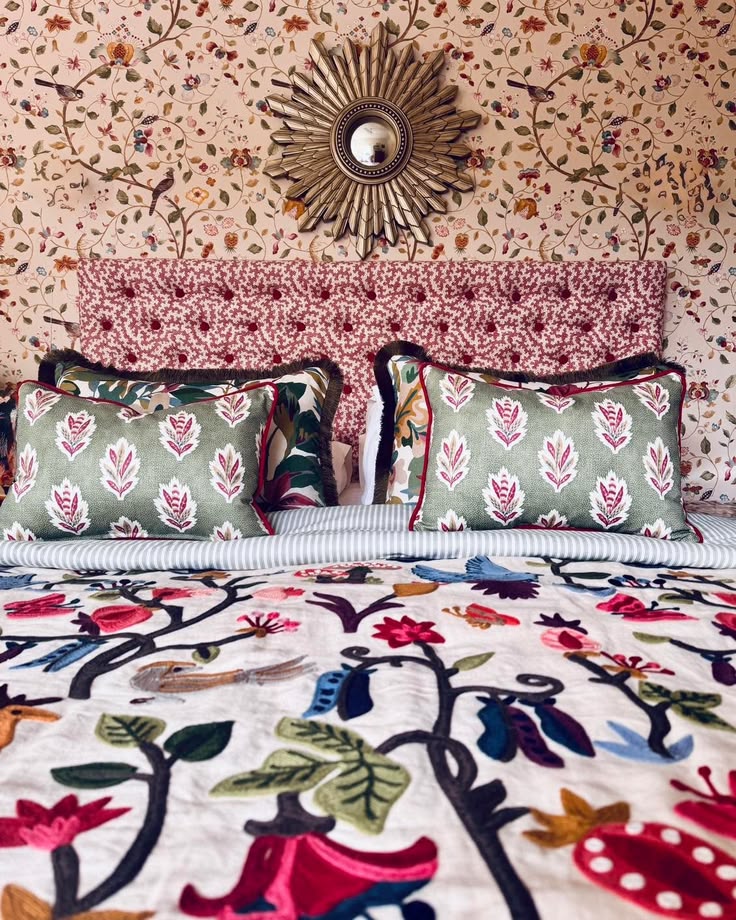 Bedroom with patterned cushions, upholstered bedhead and coordinating Sanderson Arboretum wallpaper and bedspread