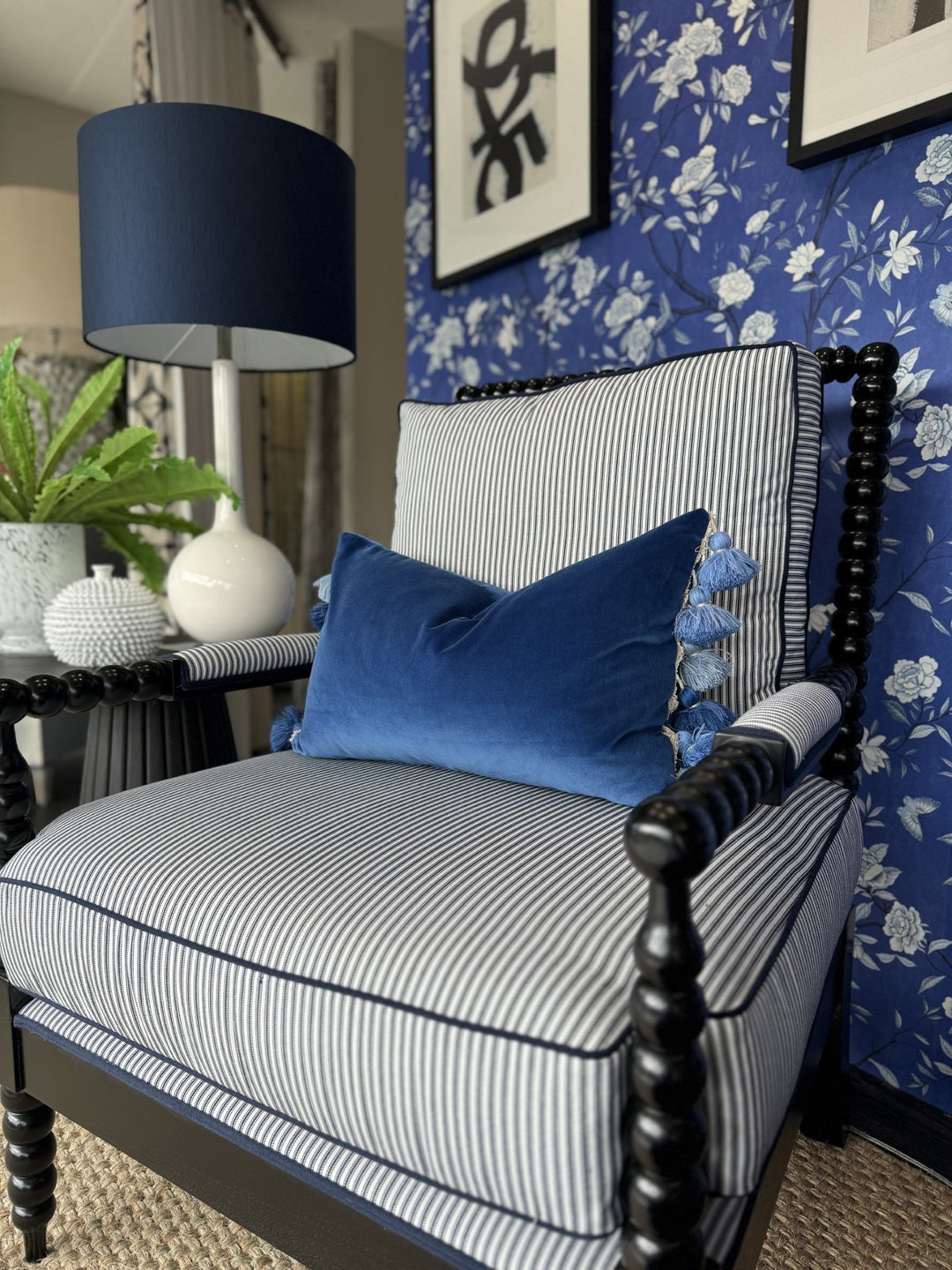 Blue and white striped armchair with a velvet cushion and floral wallpaper